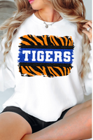 a woman wearing a white shirt with the word tigers on it